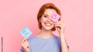 Close-up portrait of her she nice cute charming attractive cheerful girl wearing casual blue t-shirt holding in hands two draw notes positive good choice isolated on pink pastel background