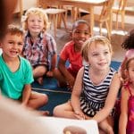 Teacher At Montessori School Reading To Children At Story Time