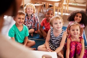 Teacher At Montessori School Reading To Children At Story Time