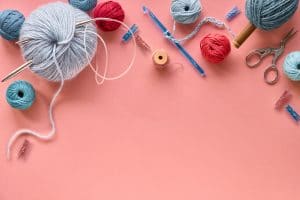 Various wool yarn and knitting needles, creative knitting hobby background with text space