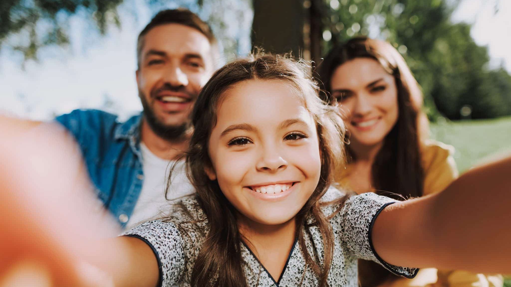 Une famille pas nombreuse mais très heureuse. Une petite fille fait un selfie avec ses parents