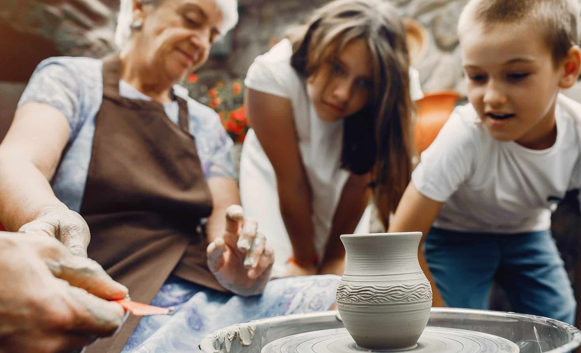 Une senior fait de la poterie avec une fille et un garçon