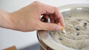 Une personne écrase un mégot de cigarette dans un cendrier, mois sans tabac
