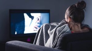 femme sur son canapé regardant un film d'horreur