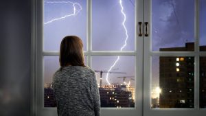 Une femme devant la fenêtre regarde l'orage