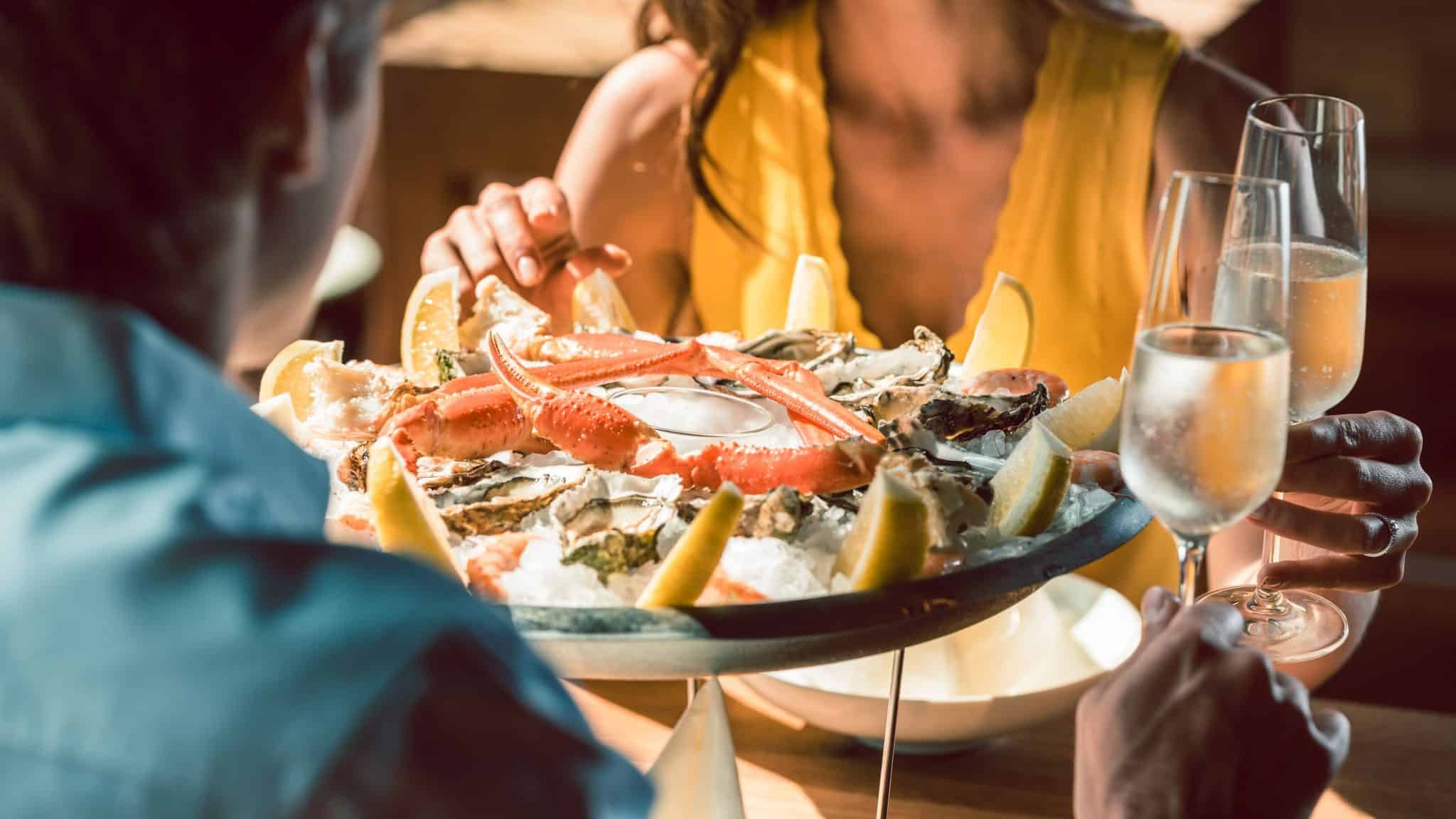 Deux personnes dégustant un plateau de fruits de mer.