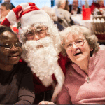 Des bénéficiaires des repas solidaires de l'association Petits Frères de Pauvres font une photo avec le Père Noël