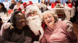 Des bénéficiaires des repas solidaires de l'association Petits Frères de Pauvres font une photo avec le Père Noël