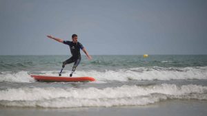 Un jeune homme amputés des deux membres inferiru surfe à l'aide deux prothèses
