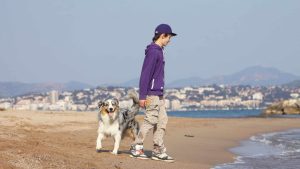 Un berger australien et son jeune maitre sur la plage.