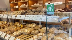 Dans une boulangerie, un étal rempli de pains avec la mention "Agriculture Biologique"