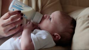 Un bébé boit au biberon du lait