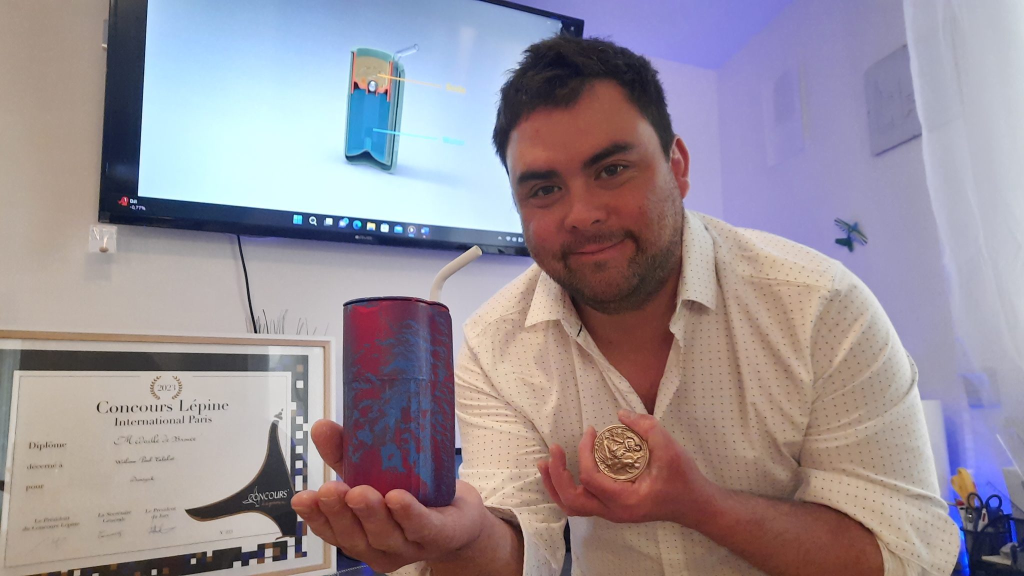 William Talabot pose avec son invention Dreasynk, et avec la médaille de bronze qu'il a reçu