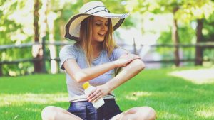 Une femme dans un parc met de la crème solaire.