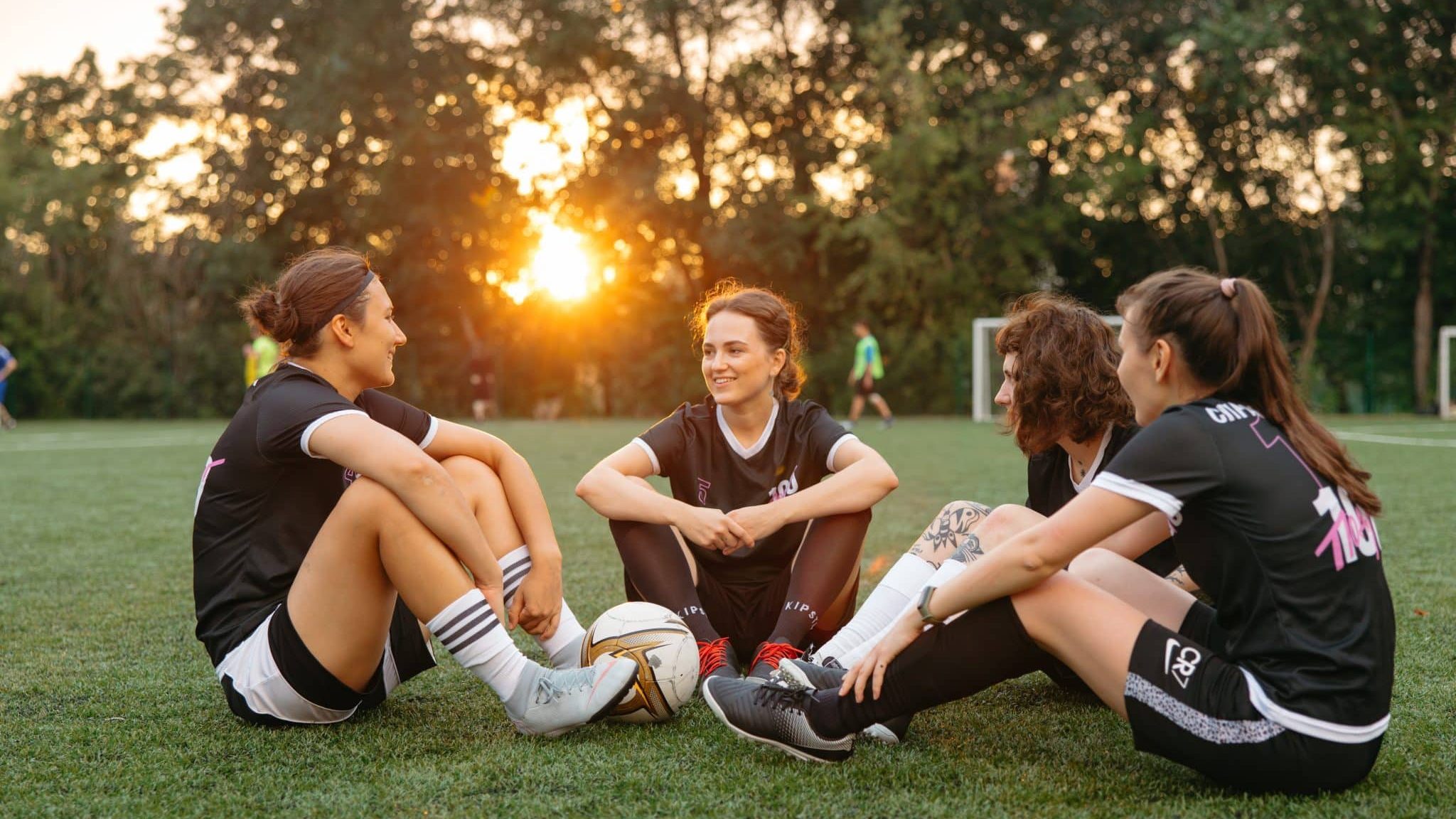 Femmes assises sur l'herbe avec un ballon de football