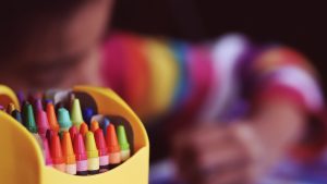 Des crayons de couleurs en premier plan en deuxième planun enfant dessine