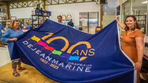 Mathilde et Erwan de Leissègues tendent un grand drapeau qui célèbre les 100 ans de Dejean Marine.