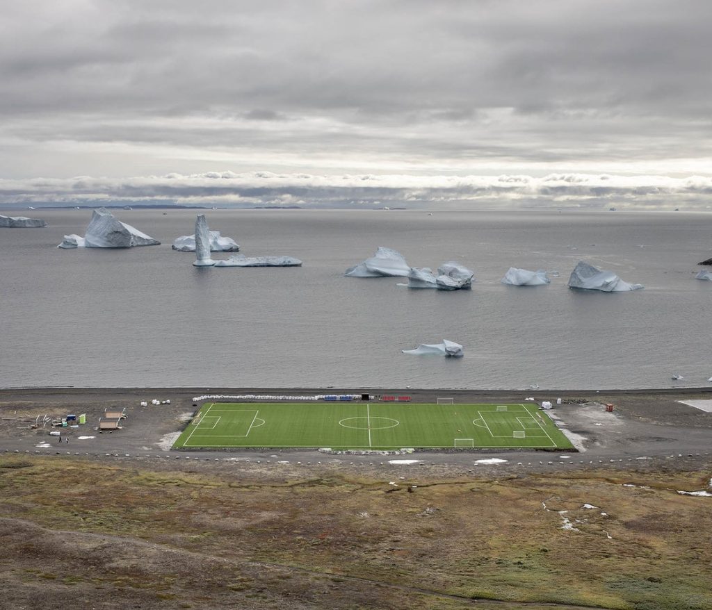 Le stade de foot en herbe synthétique de Qe-qertarsuaq, au Groenland. Il accueille le plus court championnat de football au monde qui, à cause des très basses températures, se jour une seule semaine.
