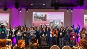 femmes élues sur une scène lors d'une cérémonie, elles saluent la foule