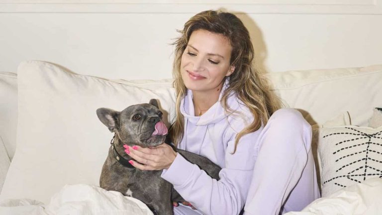 Mylène Bertaux et sa chienne Toutoute dans un lit.