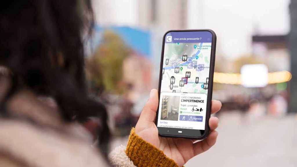 Téléphone tenu dans une main de femme avec l'application ici toilettes lancée