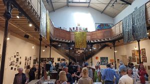 Photo de l'intérieur du Bastille design center. Il s'agit d'une grande pièce avec une importante hauteur sous plafond. L'étage est constitué d'une coursive en bois, sur piliers métalliques, qui fait le tour de la salle.