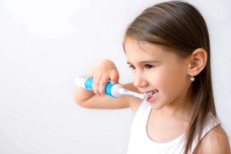 Petite fille qui se lave les dents avec une brosse à dents électrique
