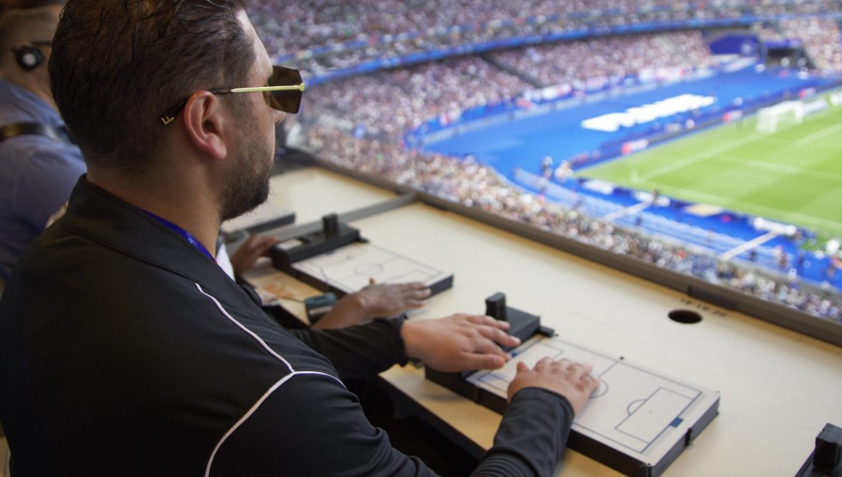 Homme aveugle qui suit un match de football avec la tablette tactile, au Stade de France