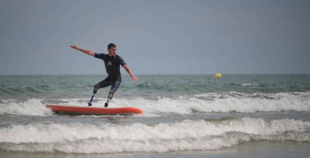 Un jeune homme amputés des deux membres inferiru surfe à l'aide deux prothèses