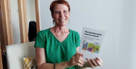 A l'occasion d'Octobre ros Christelle Pillot partage son expérience. Elle est assise sur un fauteuil et tient dans la main le livre "Plus jamais seuls face au cancer" dans lequel on peut retrouver son témoignage.