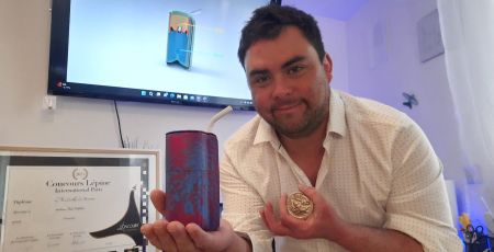 William Talabot pose avec son invention Dreasynk, et avec la médaille de bronze qu'il a reçu