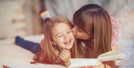 Maman qui câline sa fille en lui lisant un livre.