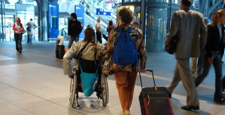 Une personne en fauteuil dans une gare.