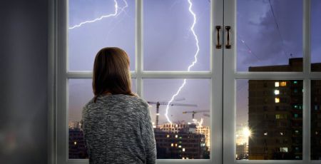 Une femme devant la fenêtre regarde l'orage