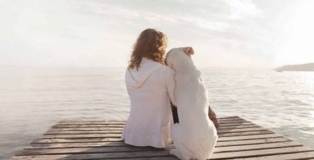 une femme et son chien de dos admirent le paysage du lac