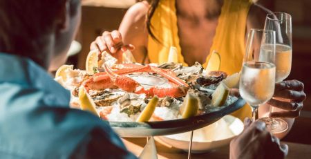 Deux personnes dégustant un plateau de fruits de mer.