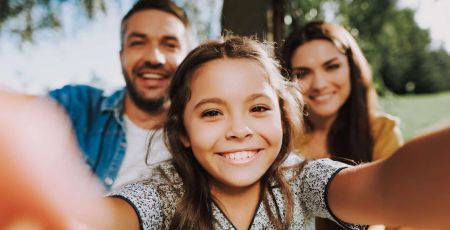 Une famille pas nombreuse mais très heureuse. Une petite fille fait un selfie avec ses parents