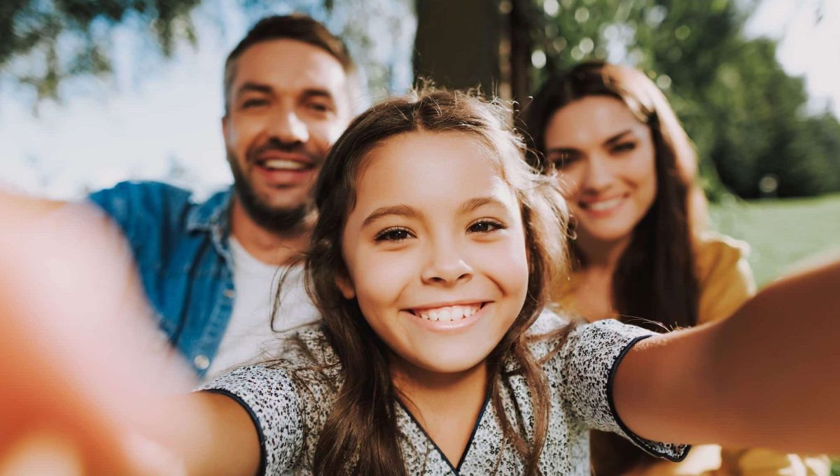 Une famille pas nombreuse mais très heureuse. Une petite fille fait un selfie avec ses parents