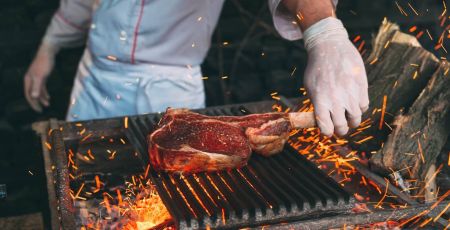 Une homme cuit de la viande rouge au barbecue