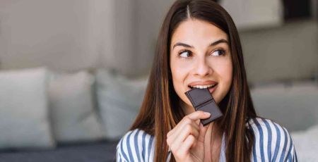 Une femme mange du chocolat noir.