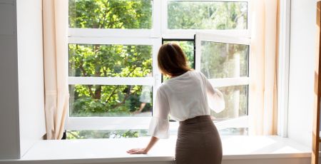 Une femme aère son logement. Prévention pollution de l'air intérieur.