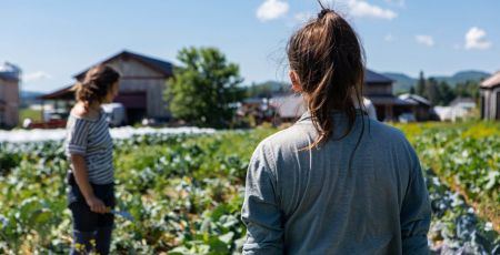 Deux agricultrices de dos, debout au milieu de leur champ, regardent à l'horizon