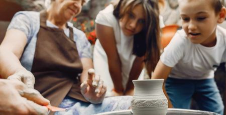 Une senior fait de la poterie avec une fille et un garçon