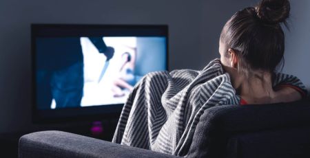 femme sur son canapé regardant un film d'horreur