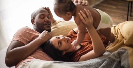 Une femme tient son bébé dans ses bras un homme ets à côté