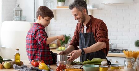Un homme cuisine avec son fils.