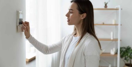 Femme réglant un thermostat pour faire des économies d'énergie