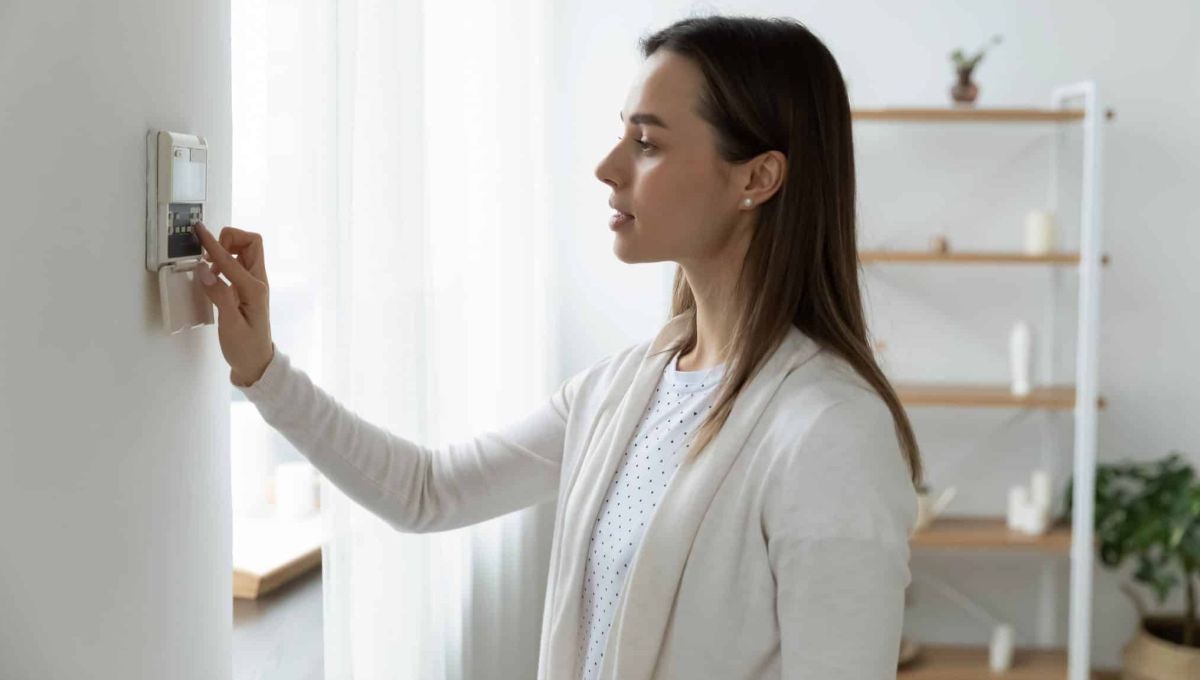 Femme réglant un thermostat pour faire des économies d'énergie