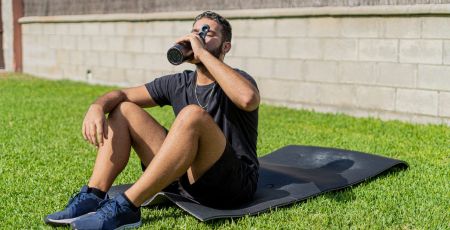 Un homme sur un tapis d'exercice boit.
