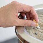 Une personne écrase un mégot de cigarette dans un cendrier, mois sans tabac